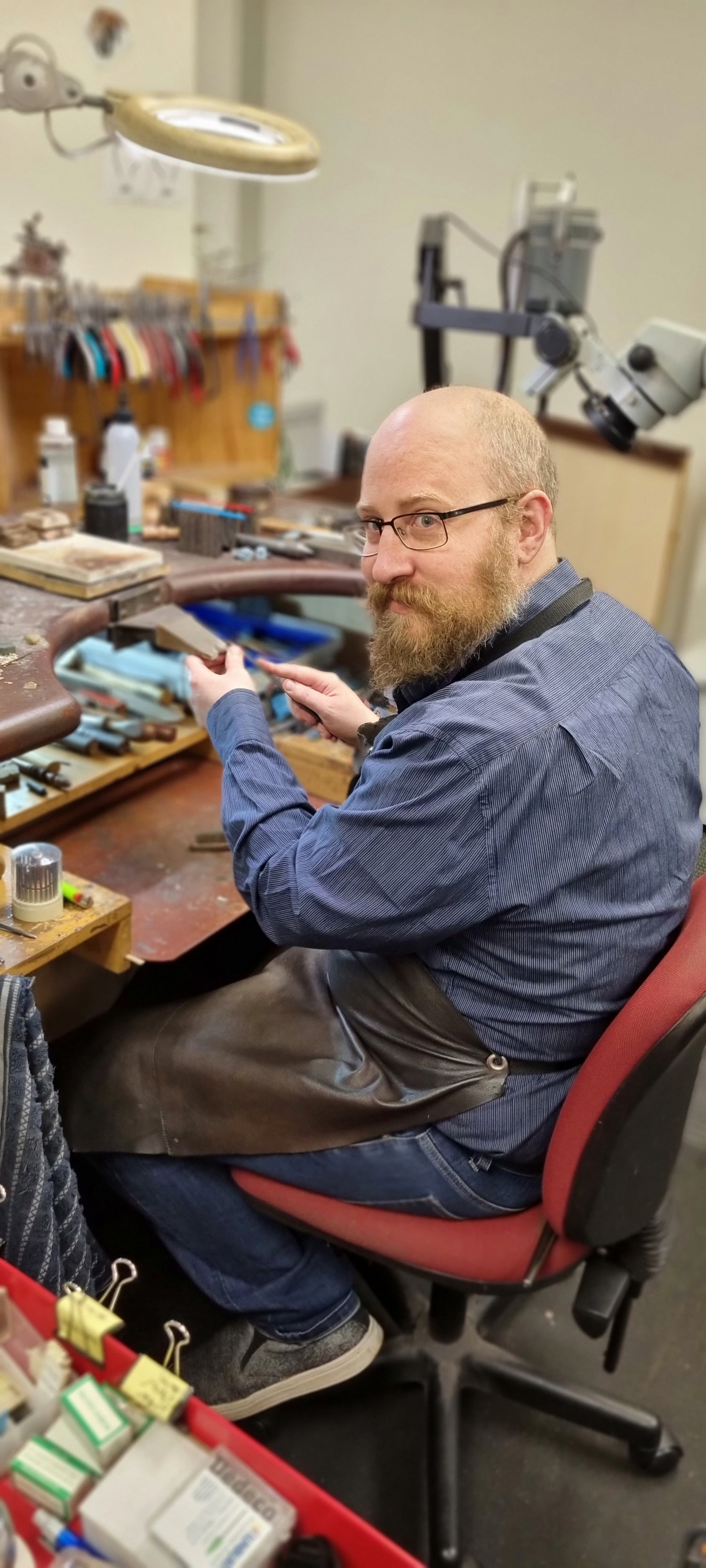 Smiling male jeweller at his bench
